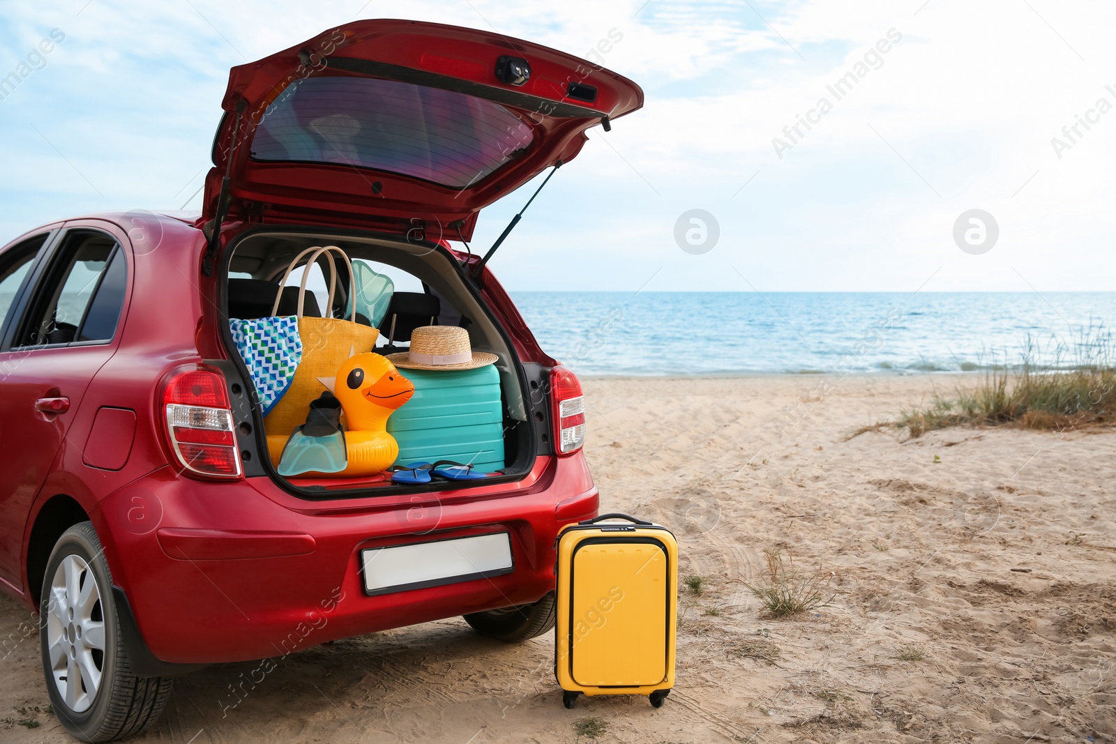 Photo of Red car luggage on beach, space for text. Summer vacation trip