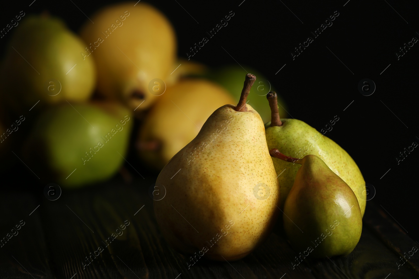 Photo of Fresh ripe pears on dark table against blurred background