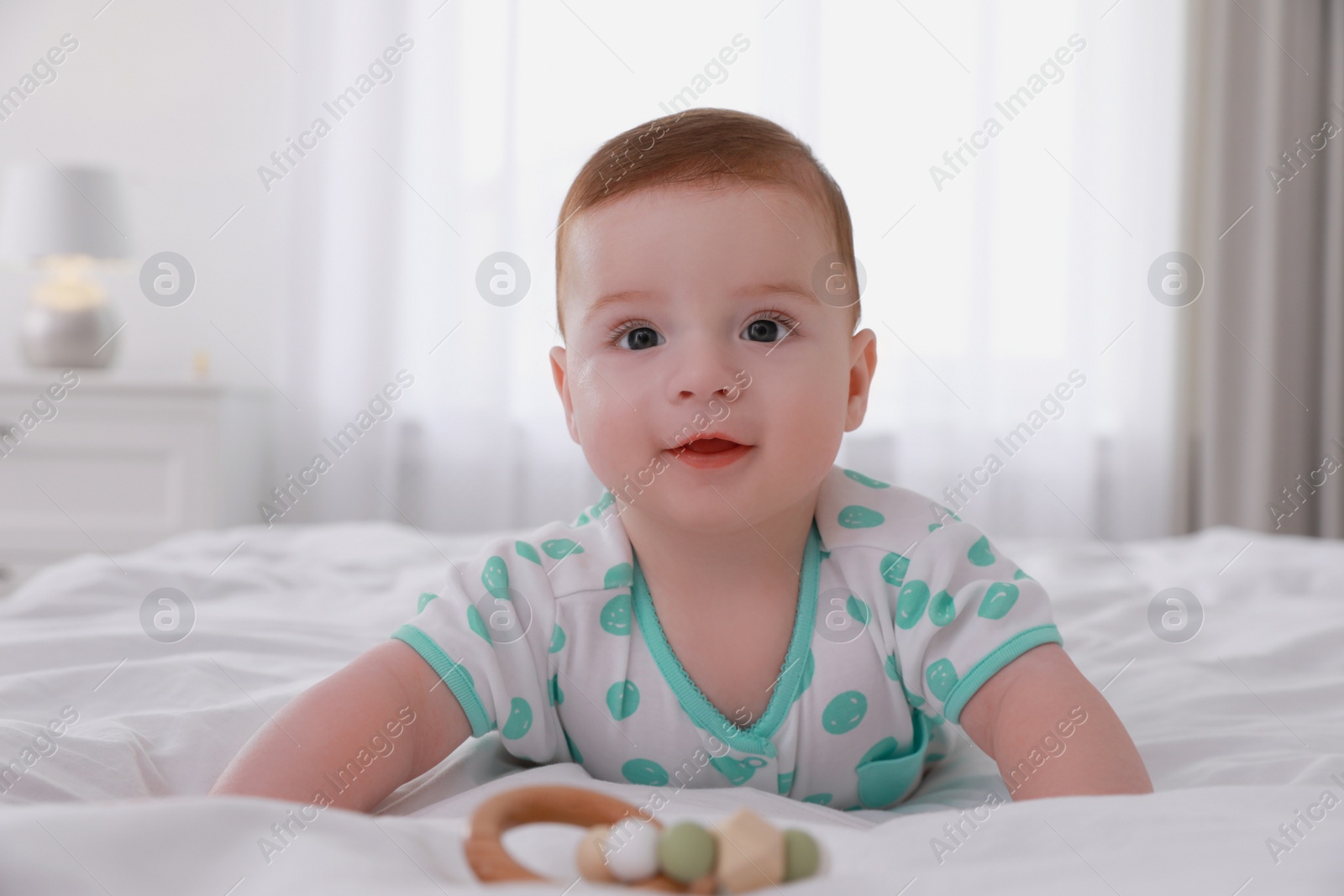 Photo of Cute little baby lying on bed with soft blanket indoors