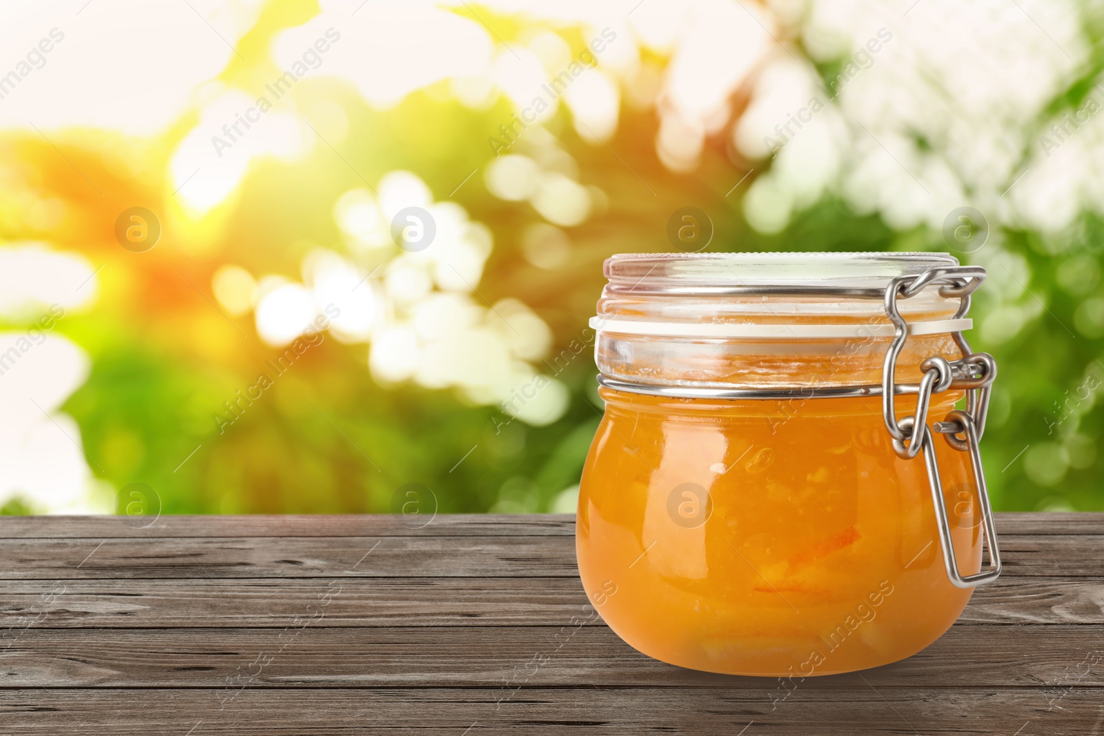 Image of Jar of orange jam on wooden table against blurred background, space for text