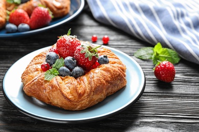 Photo of Fresh delicious puff pastry with sweet berries on dark wooden table