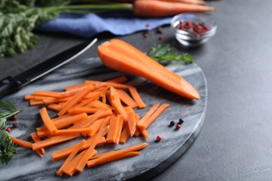 Cut raw carrot and marble board on grey table, closeup