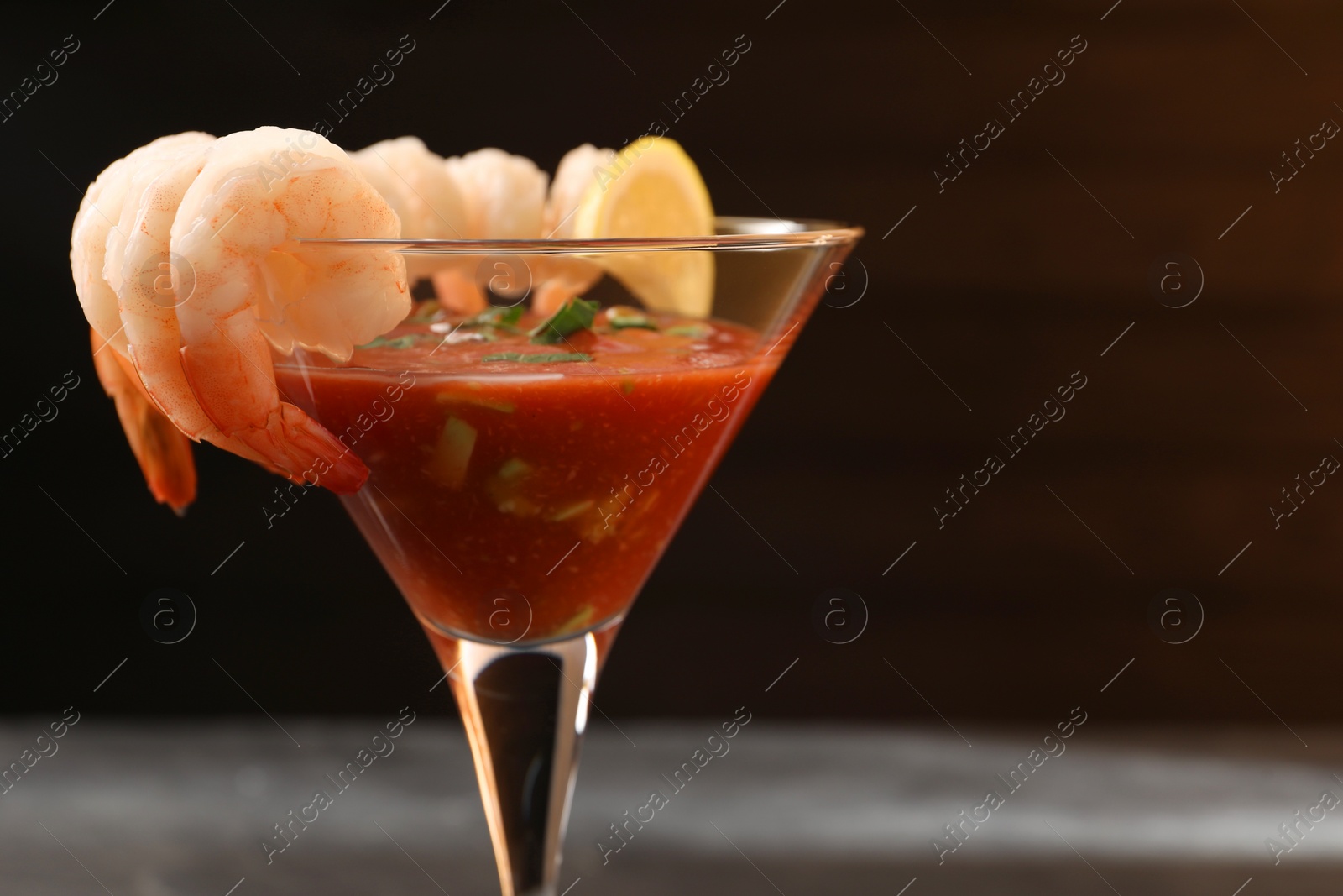 Photo of Tasty shrimp cocktail with sauce in glass on blurred background, closeup. Space for text