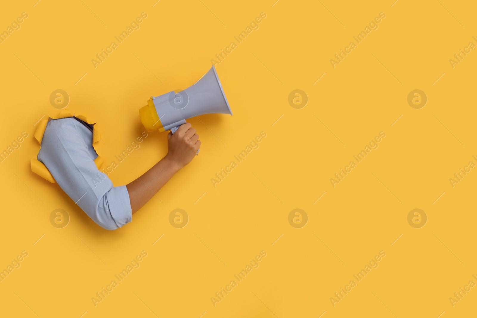 Photo of Special promotion. Woman holding megaphone through hole in orange paper, closeup. Space for text