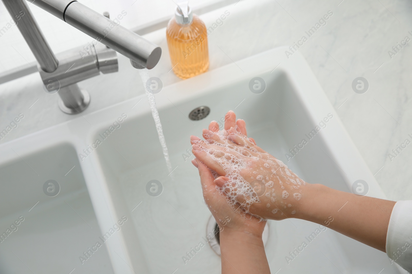 Photo of Woman washing hands with liquid soap at home, closeup