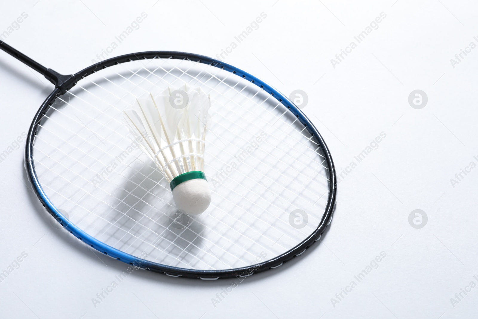 Photo of Feather badminton shuttlecock and racket on gray background, space for text