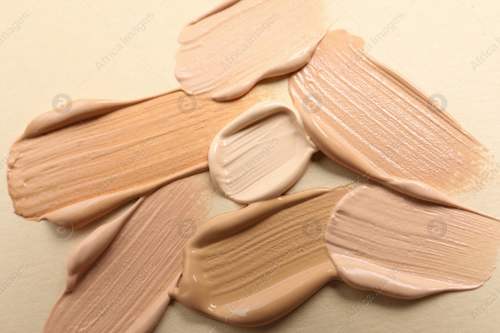 Photo of Samples of skin foundation on beige background, closeup