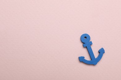 Photo of Anchor figure on pale pink background, top view. Space for text