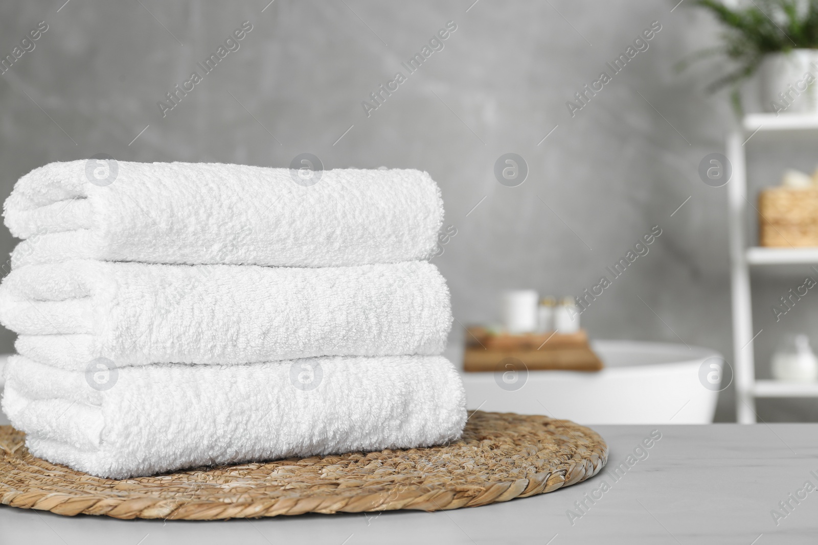 Photo of Stacked bath towels on light table in bathroom. Space for text