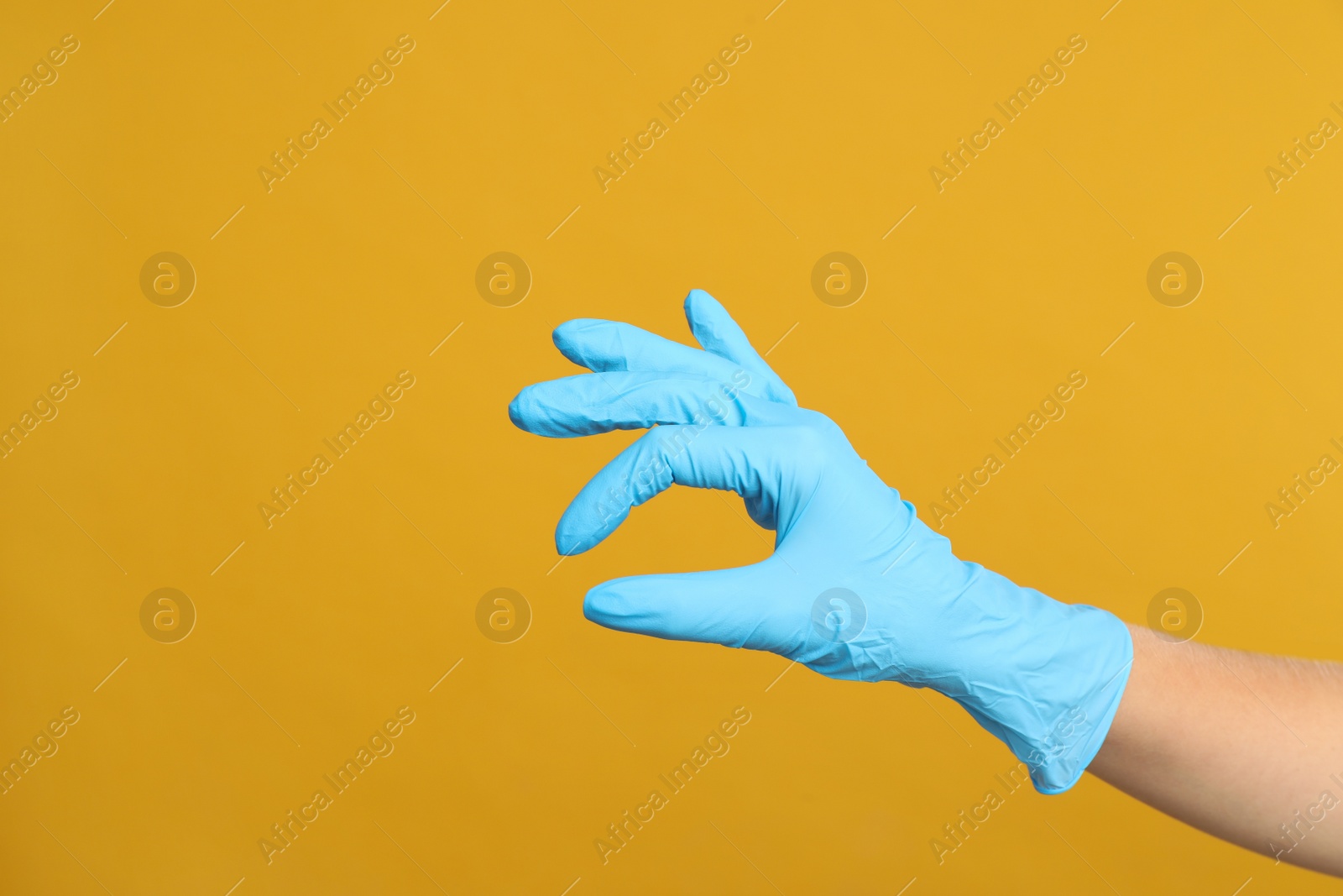 Photo of Doctor in medical gloves showing OK gesture on yellow background, closeup. Space for text