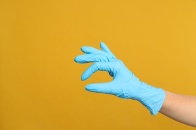 Photo of Doctor in medical gloves showing OK gesture on yellow background, closeup. Space for text