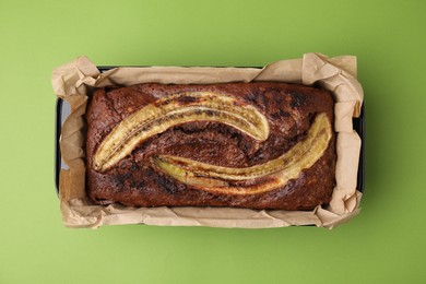 Delicious banana bread on green background, top view
