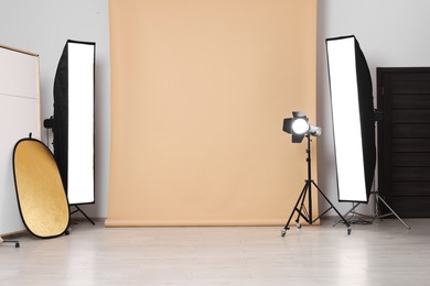 Photo of Beige photo background and professional lighting equipment in studio