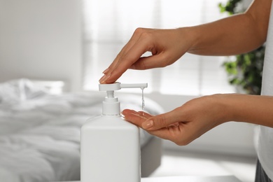 Woman applying hand sanitizer indoors, closeup. Personal hygiene during COVID-19 pandemic