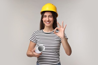 Photo of Architect with hard hat and draft showing ok gesture on light grey background