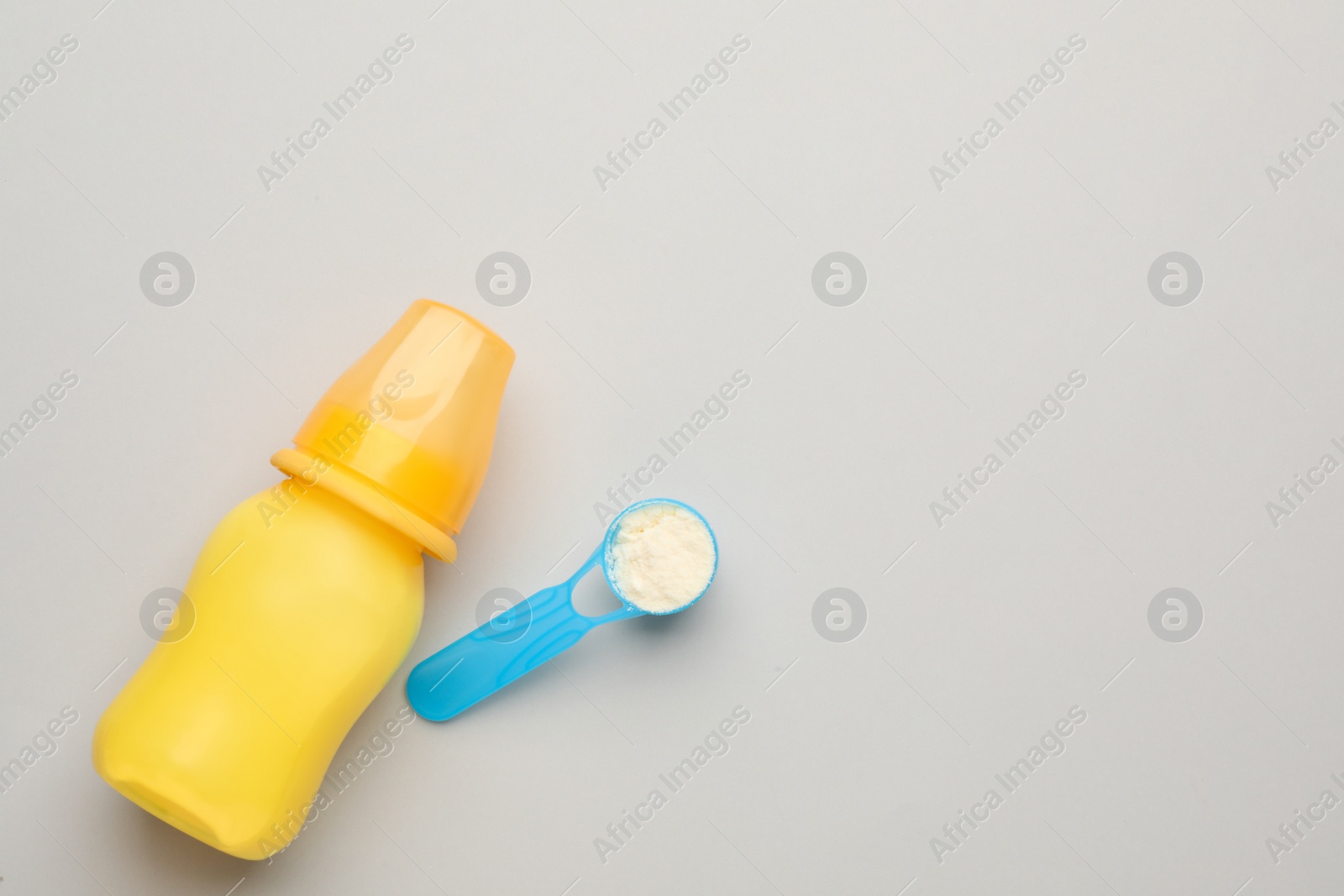 Photo of Feeding bottle with infant formula and powder on light background, flat lay. Space for text