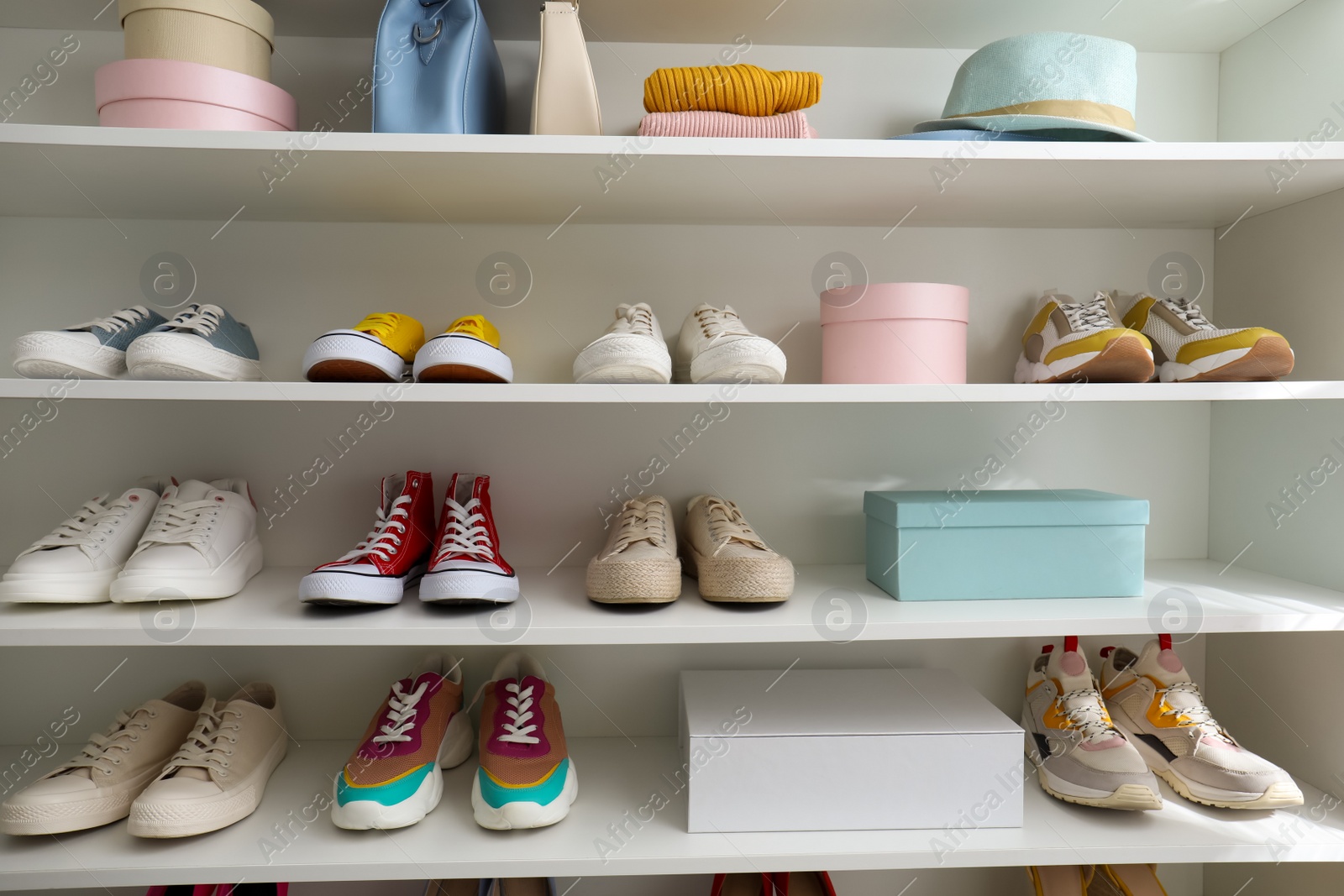 Photo of White shelving unit with collection of colorful sneakers and accessories