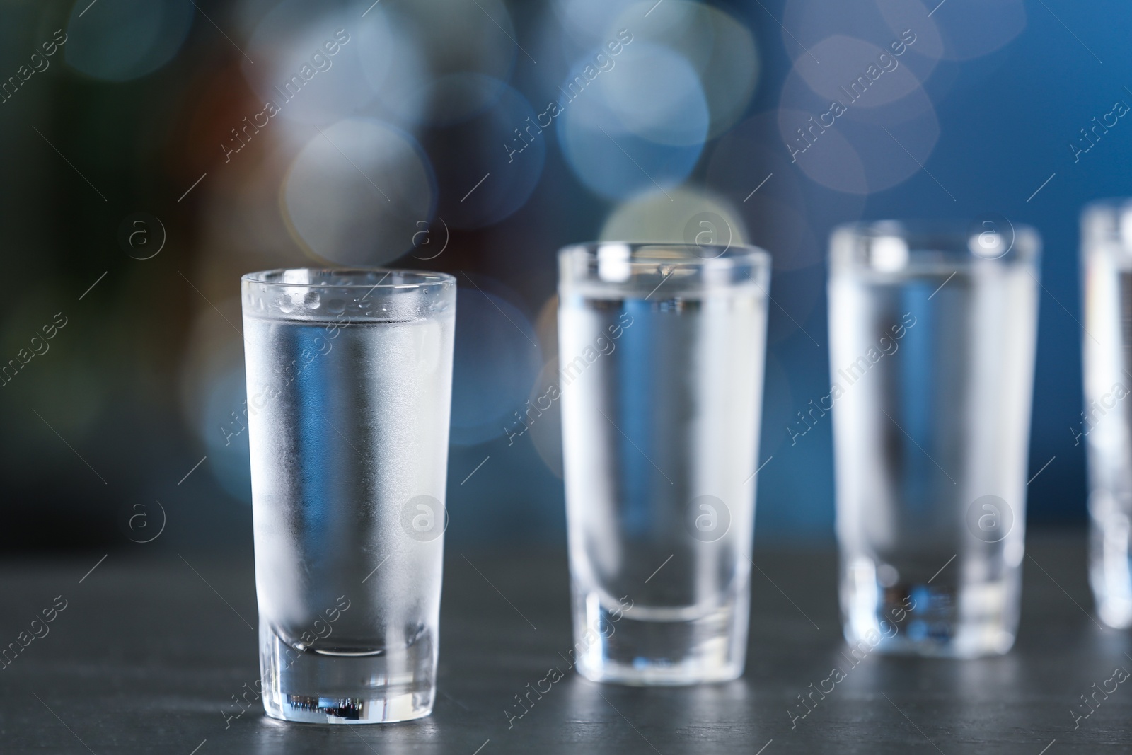 Photo of Shot of vodka on table against blurred background. Space for text