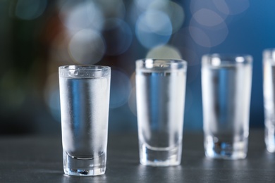 Photo of Shot of vodka on table against blurred background. Space for text