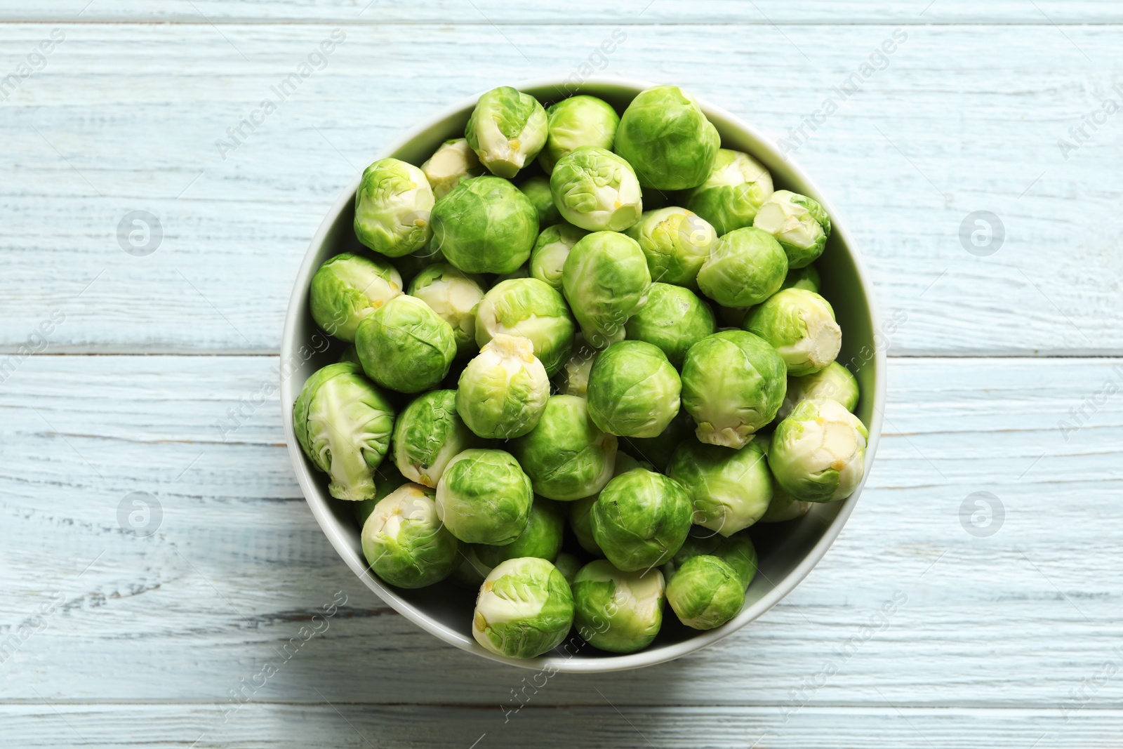 Photo of Bowl of fresh Brussels sprouts on wooden background, top view