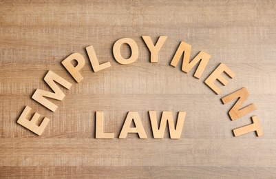 Flat lay composition with words EMPLOYMENT LAW on wooden background