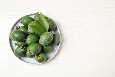Photo of Fresh green feijoa fruits on white wooden table, top view. Space for text