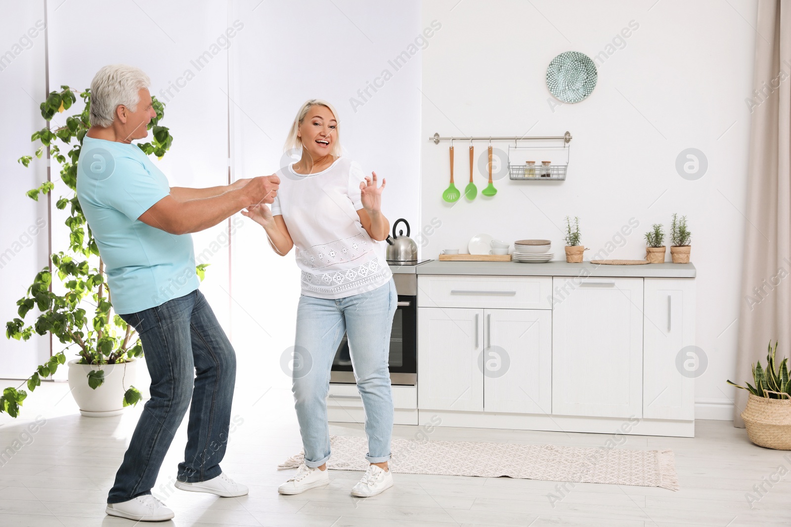 Photo of Happy mature couple dancing together in kitchen