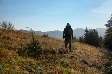 Photo of Tourist with backpack in mountains, back view. Space for text