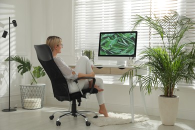Photo of Woman resting on chair near workplace in room. Interior design
