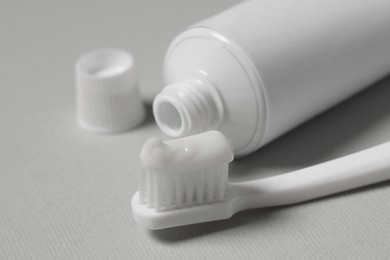 Photo of Plastic toothbrush with paste and tube on grey background, closeup
