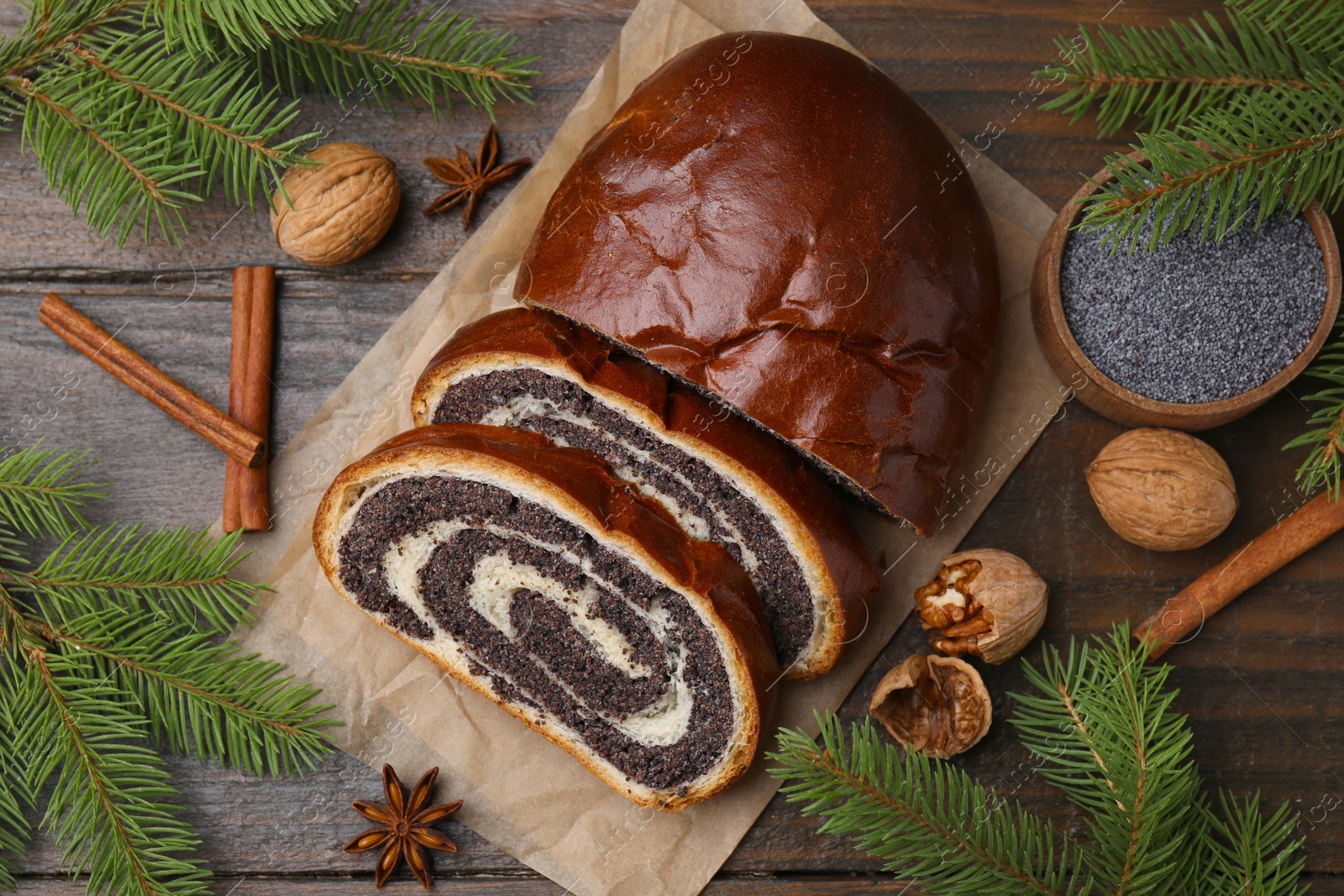 Photo of Flat lay composition with cut poppy seed roll and fir branches on wooden table. Tasty cake