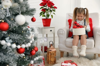 Photo of Cute little girl with box of Christmas balls at home