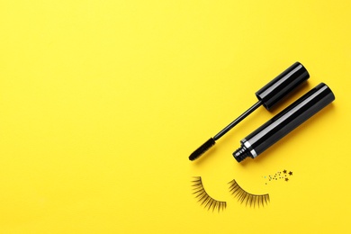 Photo of False eyelashes and mascara on yellow background, flat lay. Space for text