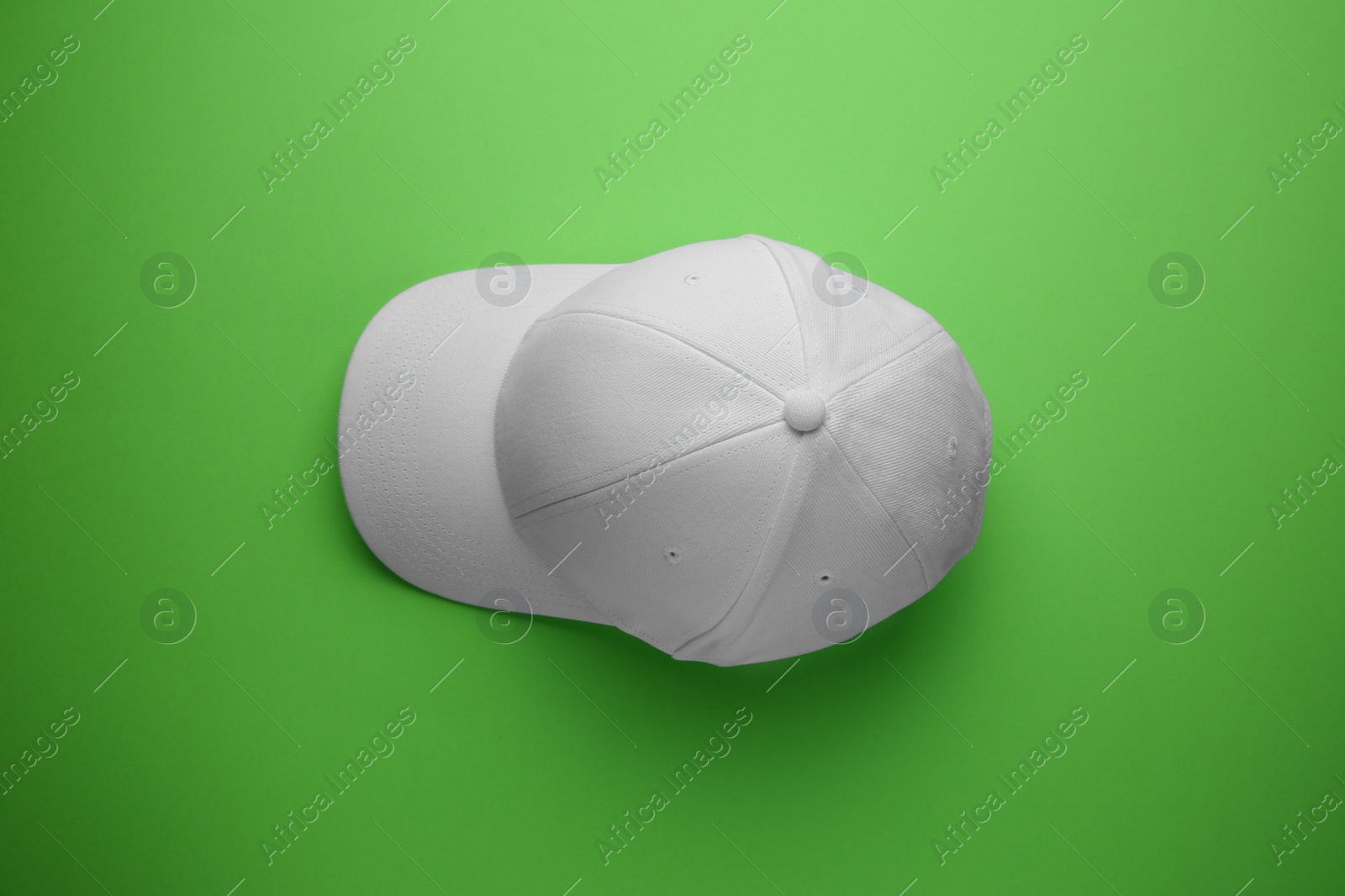 Photo of Stylish white baseball cap on light green background, top view