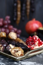 Photo of Delicious sweet churchkhelas and pomegranate on textured table, closeup