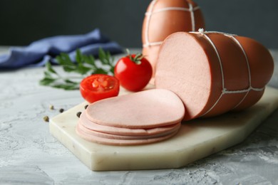 Delicious boiled sausage with tomatoes and spices on grey textured table, closeup