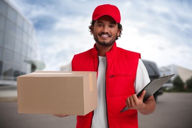 Happy courier with parcel and clipboard outdoors