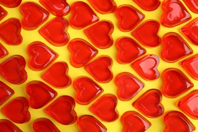 Photo of Sweet heart shaped jelly candies on yellow background, flat lay