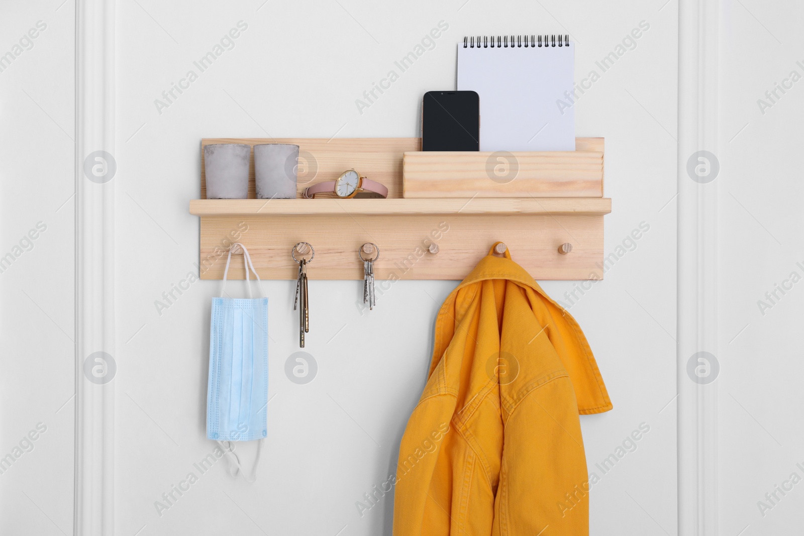 Photo of Wooden hanger for keys with different stuff on white wall