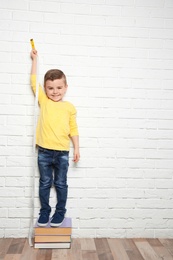Little boy measuring his height near brick wall