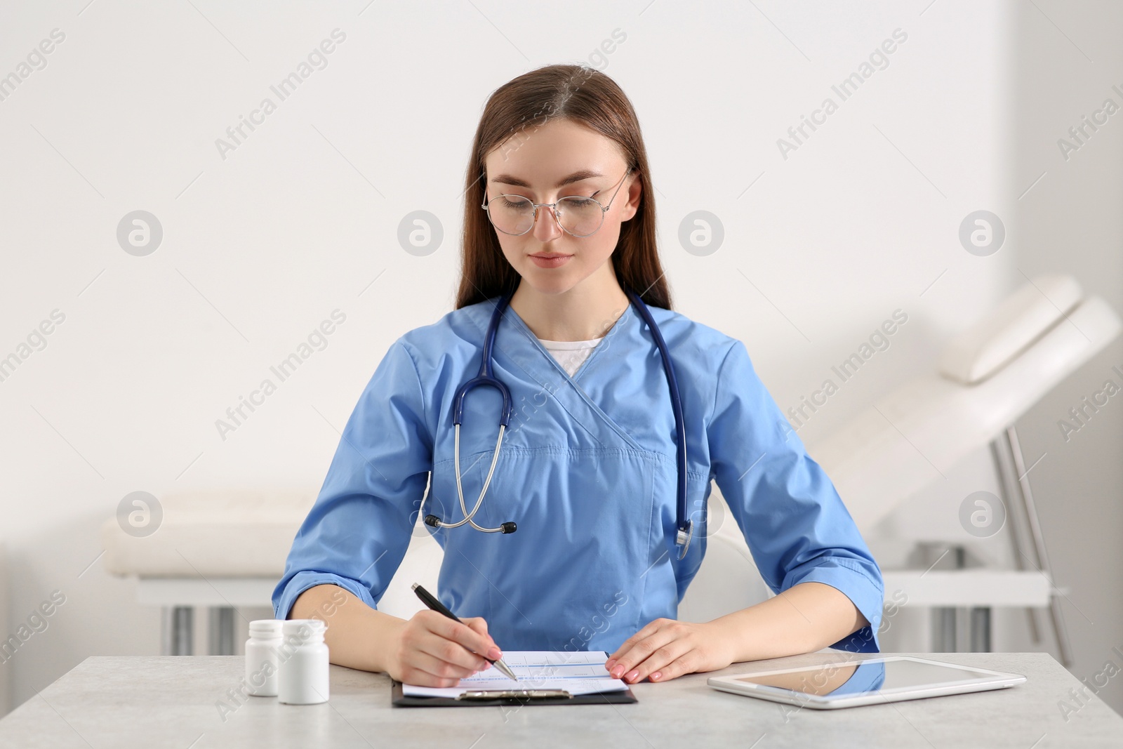 Photo of Doctor filling patient's medical card at table in clinic