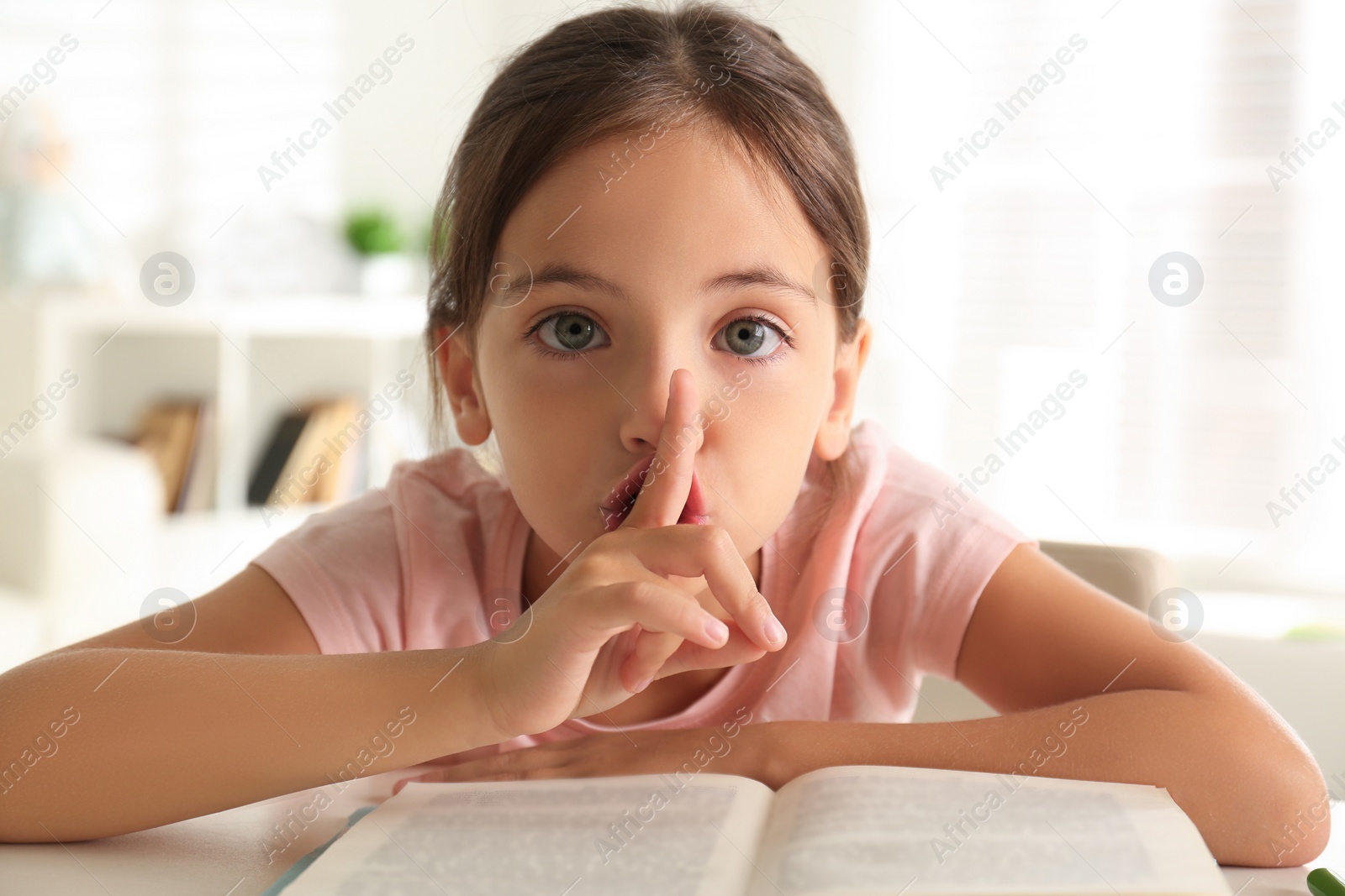 Photo of Little girl doing homework at table indoors