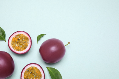 Photo of Fresh ripe passion fruits (maracuyas) with leaves on light background, flat lay. Space for text