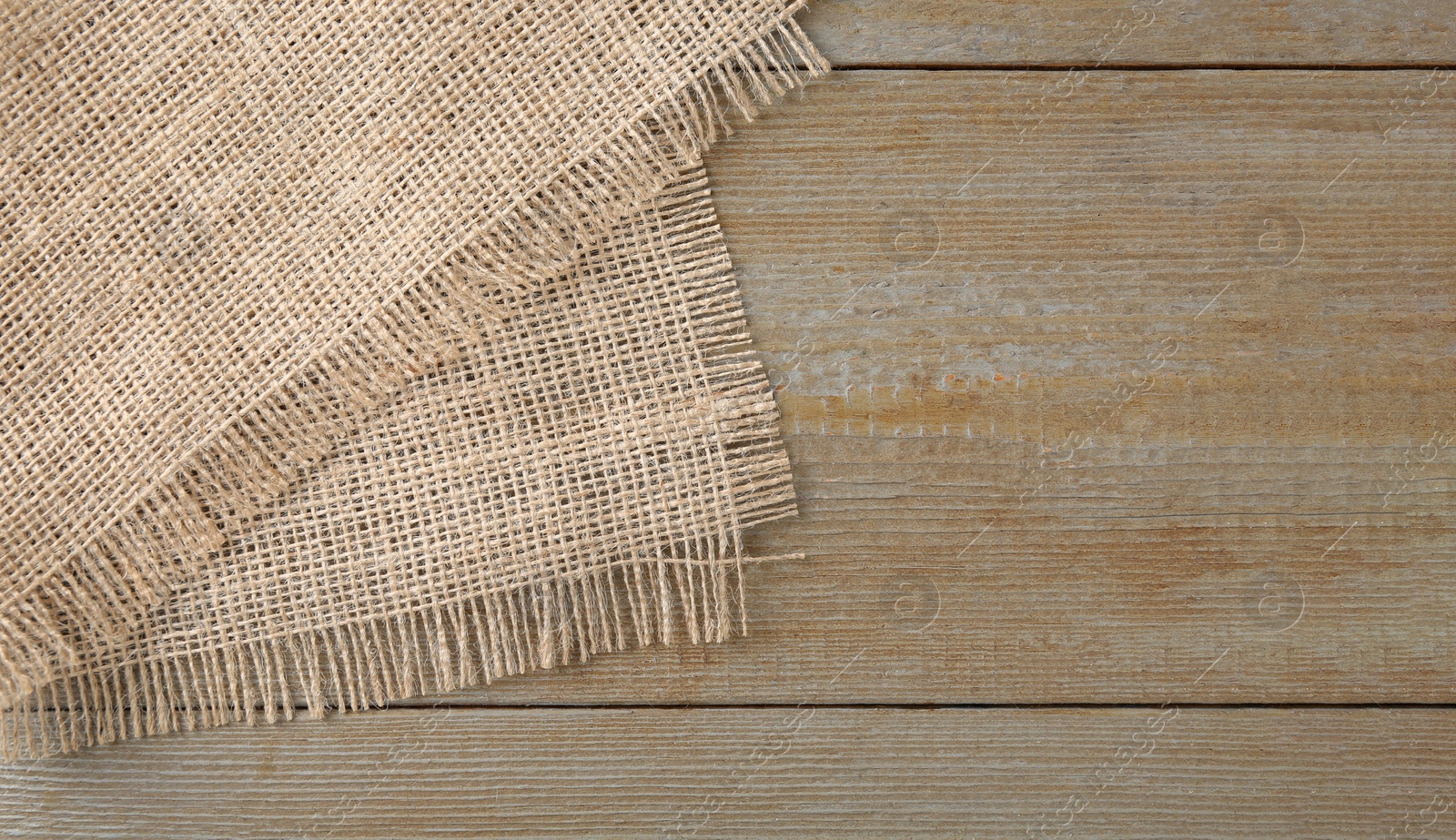 Photo of Piece of burlap fabric on wooden table, top view. Space for text