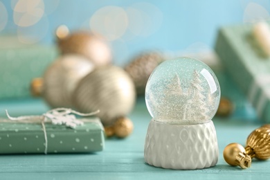 Photo of Beautiful snow globe and Christmas balls on light blue table