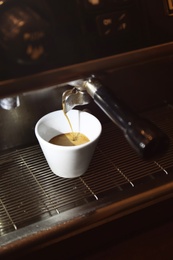 Photo of Preparing fresh aromatic coffee on modern machine, closeup