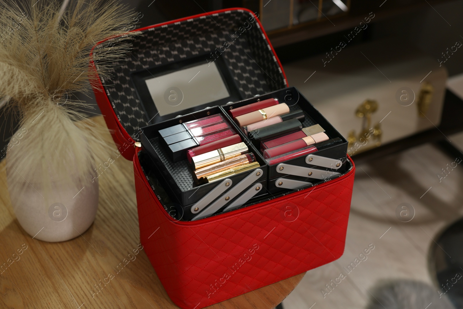 Photo of Beautician case with makeup products and decorative plants in vase on wooden table indoors