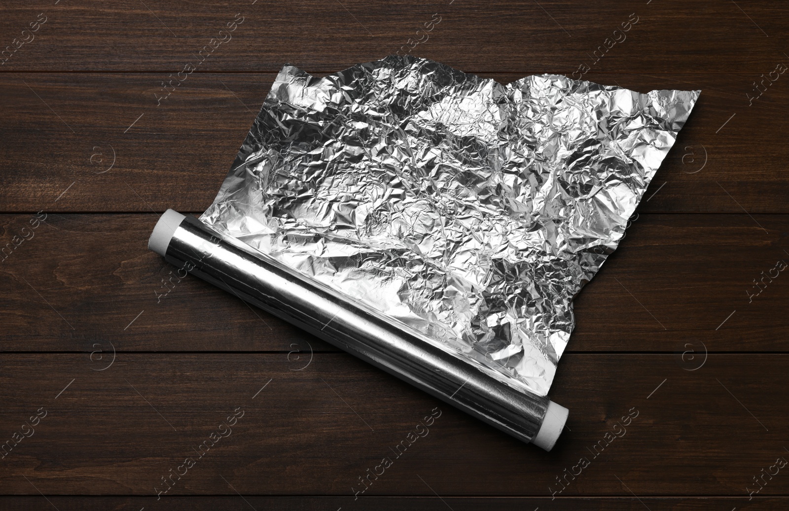 Photo of Roll of foil paper on wooden table, top view