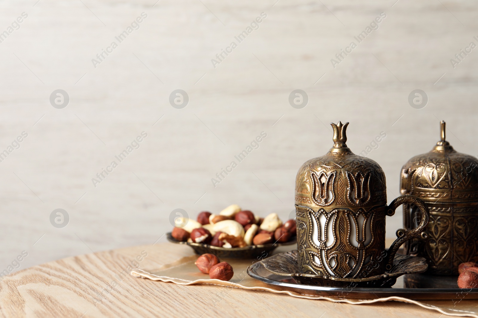 Photo of Tea and nuts served in vintage tea set on wooden table, space for text