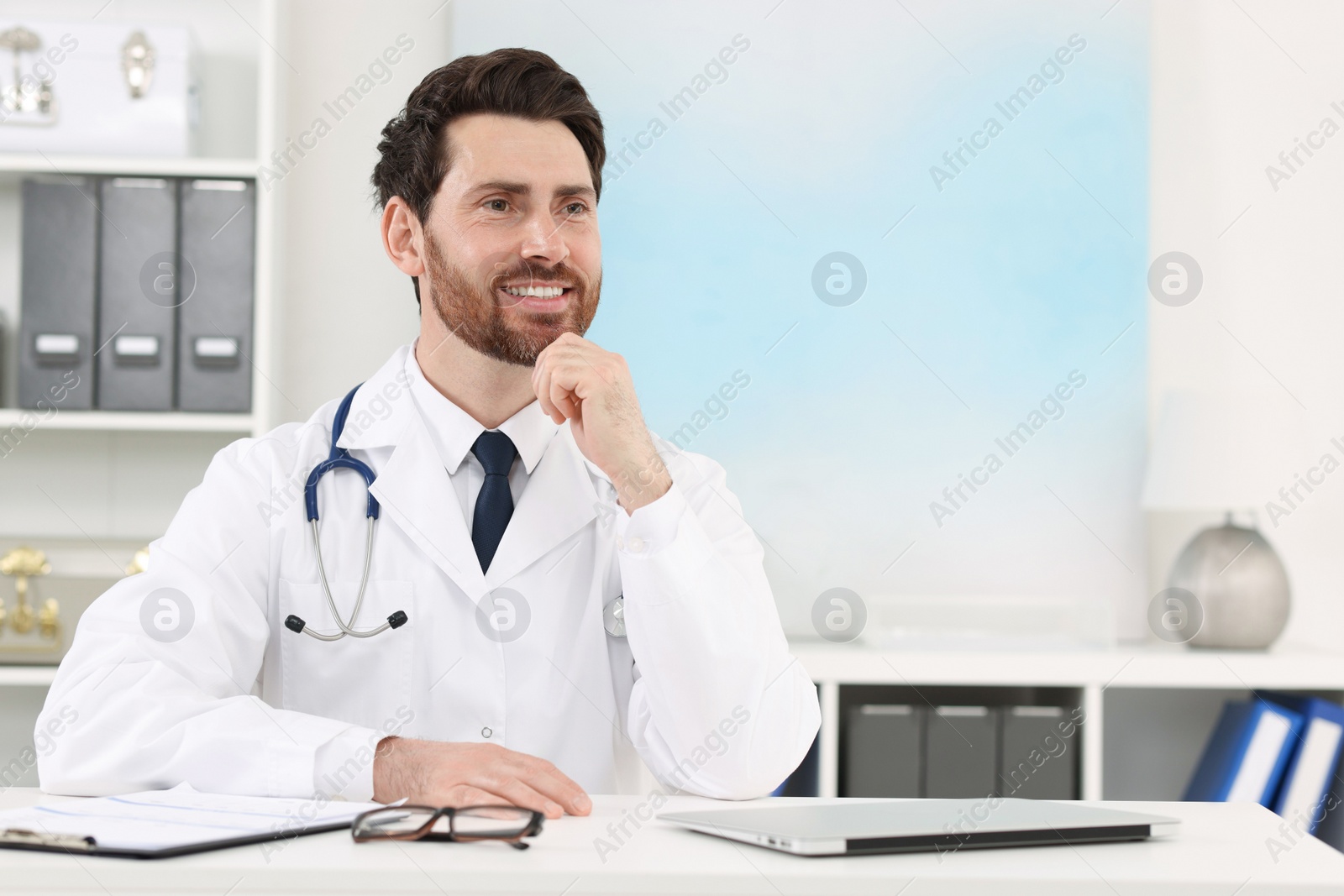 Photo of Medical consultant with stethoscope at table in clinic, space for text